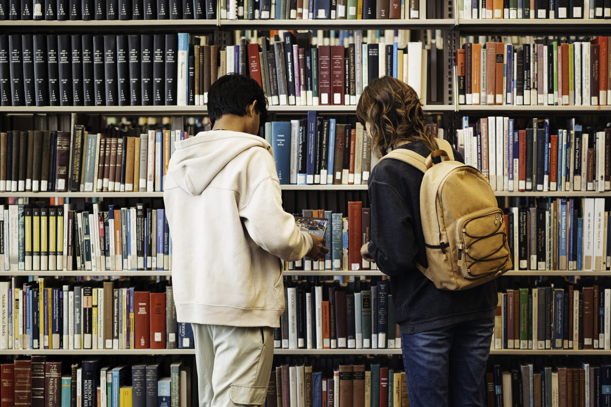 Two students in front of a bookcase.
