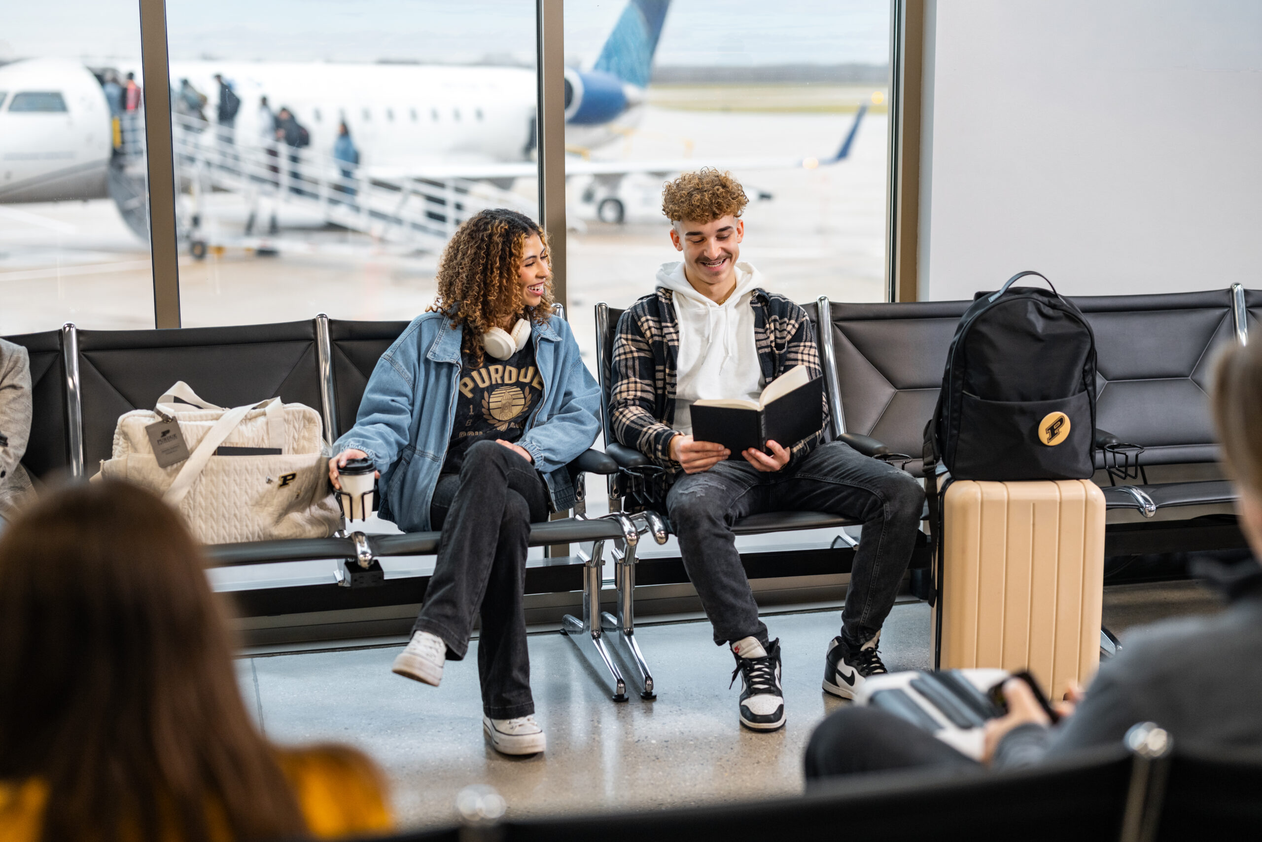 Two students sitting in an airport looking at a book
