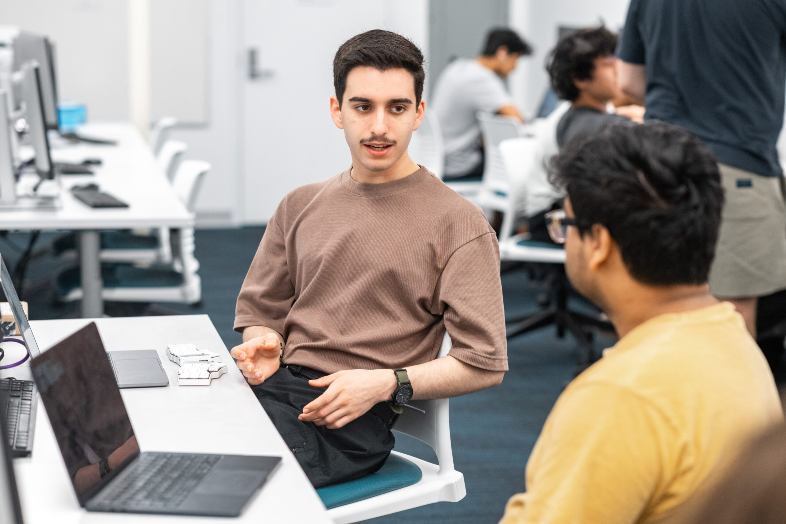 Two students in a computer lab talking.