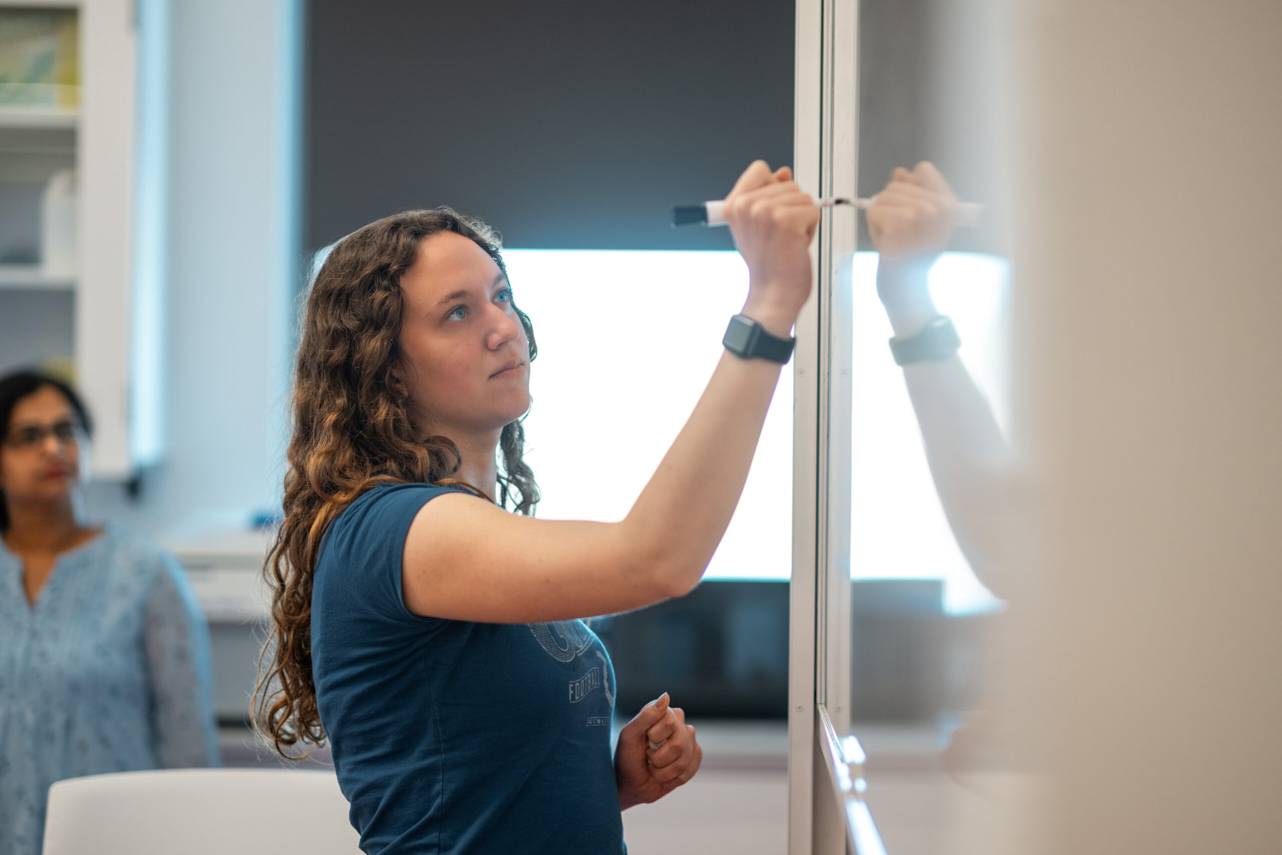 A woman writing on a white board