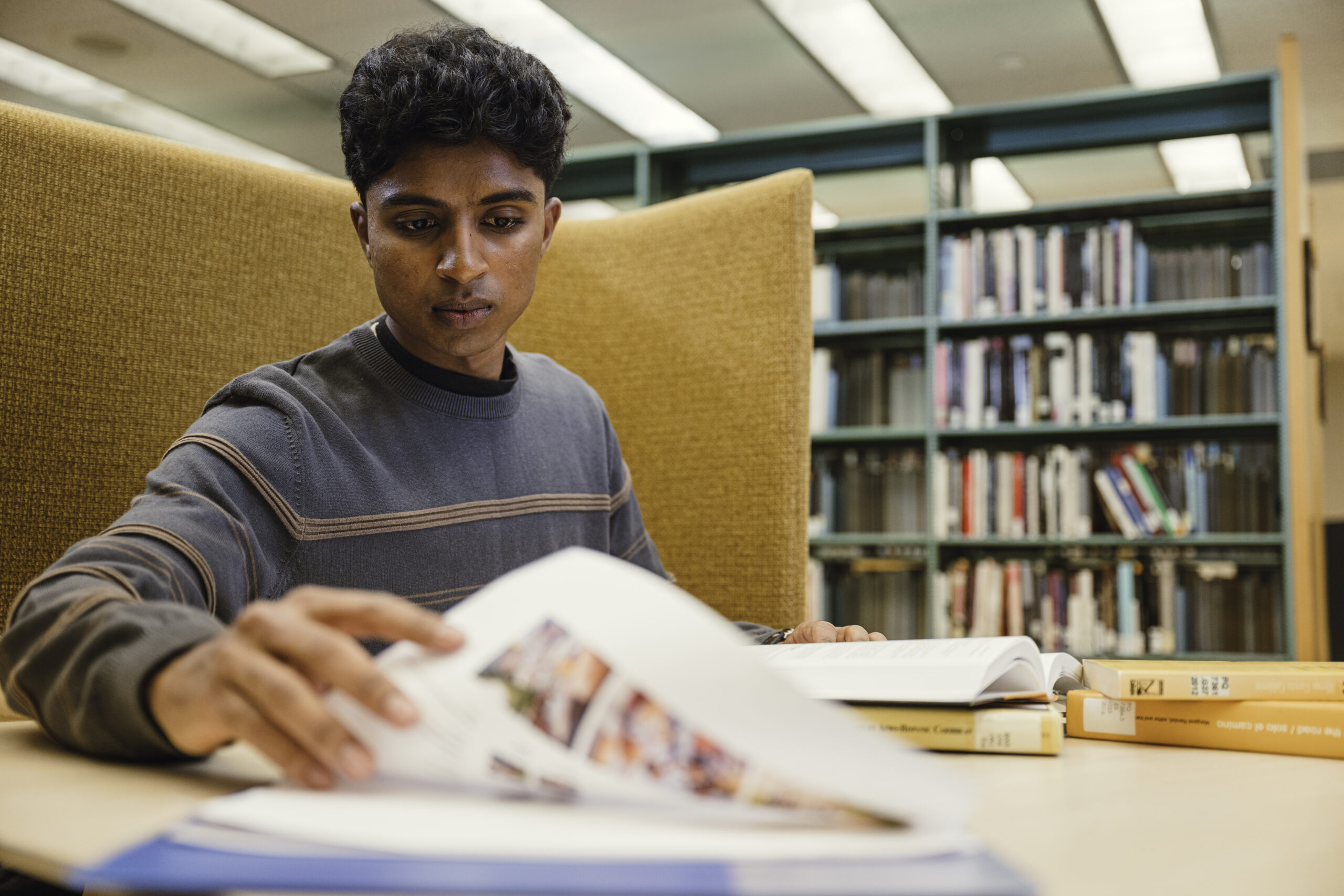 Student in a library booth flipping a page.